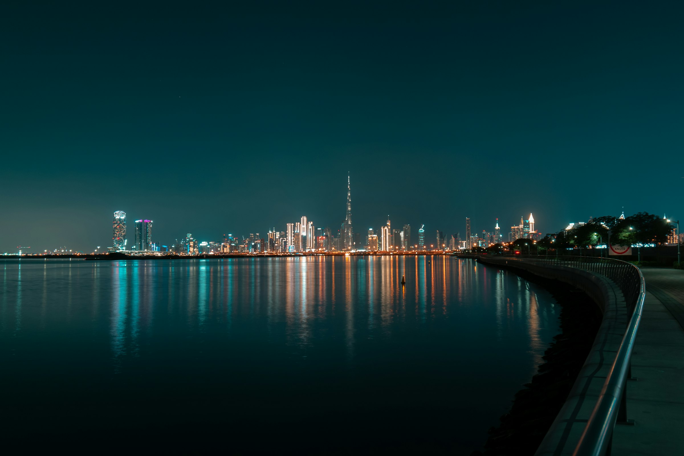 Dubai skyline lit up across calm water at night